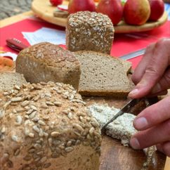Nahaufnahme einer Hand, die Brot schneidet