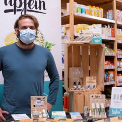 Ein Mann steht an einem Tisch, darauf eine Auswahl von Biokosmetik von Lipfein