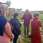 Bio-Landwirt auf seinem Acker spricht zu einer Gruppe Menschen