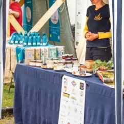 Eine Mitarbeiterin der FAIRE steht am Stand mit Produkten zur Präsentation