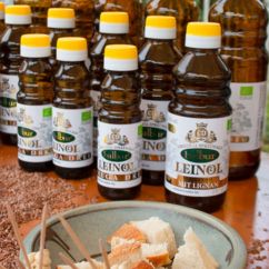 Flaschen mit Bio-Leinöl stehen hinter einer Schale mit Brotstücken auf einem Tisch