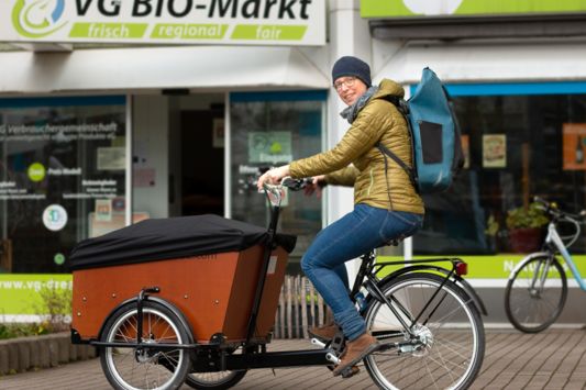 Frau fährt Lastenrad vor der VG