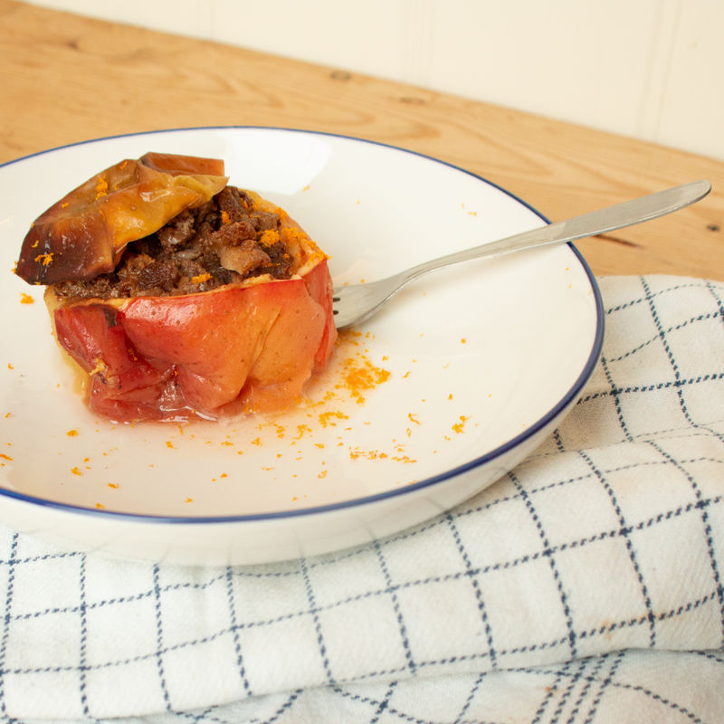 Ein Bratapfel mit Orange-Nuss Füllung auf einem Teller mit einer Gabel