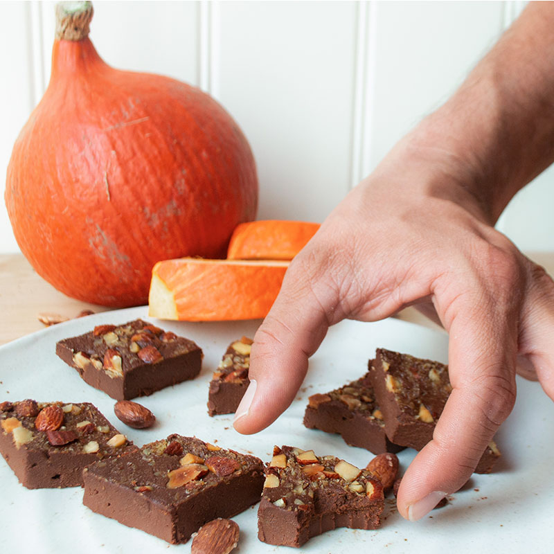 Hand greift nach Kürbisfudge auf einem Teller