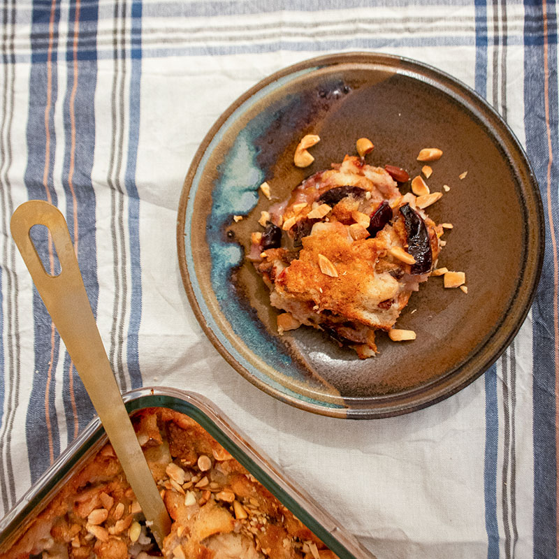 Teller mit Pflaumen-Auflauf auf einem Tischtuch