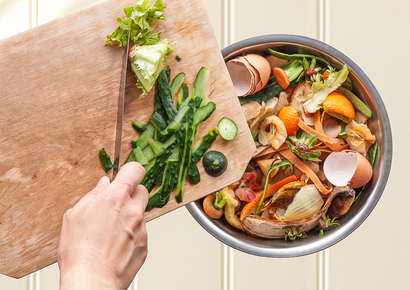 Hand schiebt Lebensmittel in den Müll